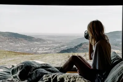 a woman sitting on a bed looking at a view at Vega in Llangollen