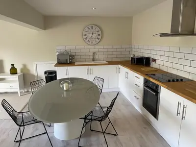 a kitchen with a table and chairs and a clock on the wall at Townhouse Apartment in Oswestry