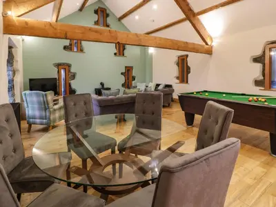 a living room with a glass table and a pool table at The Barn by Lyons in Talybont