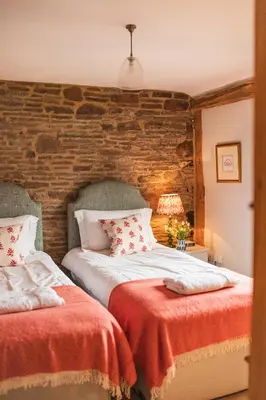two beds in a bedroom with a brick wall at Meadow End Barn in Dorstone