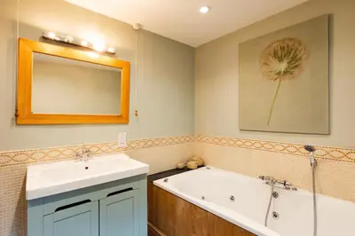 a bathroom with a tub and a sink and a mirror at Meadow End Barn in Dorstone