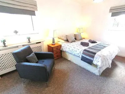 a bedroom with a bed and a chair and a window at Cartref Bach in Llanybydder