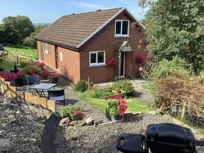 a small brick house with a garden and flowers at Cartref Bach in Llanybydder
