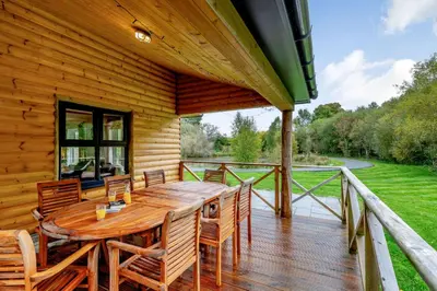 a wooden deck with a wooden table and chairs at Rhosllyn Retreats - Lakeside Lodge in Rhayader