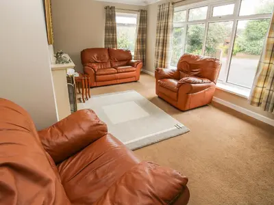 a living room with leather furniture and a window at The Highlands in Church Stretton