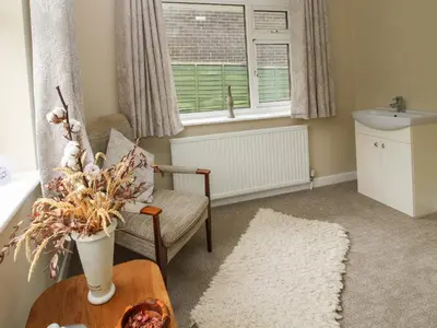 a living room with a table and a chair and a window at The Highlands in Church Stretton
