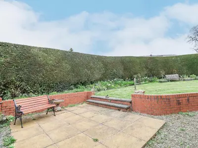 a bench sitting on a patio next to a brick wall at The Highlands in Church Stretton