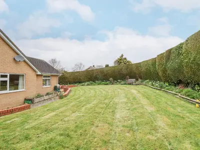 a yard with a hedge and a house at The Highlands in Church Stretton