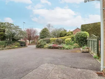 a driveway of a house with a fence and flowers at The Highlands in Church Stretton