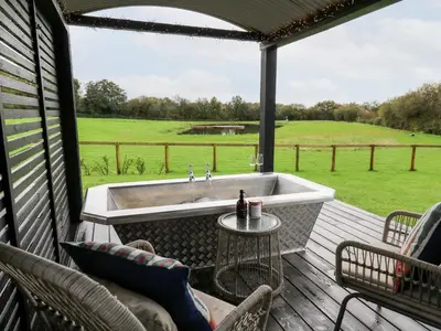 a screened in tub on a deck with a view of a field at Dragonfly Shepherd's Hut in Aberaeron