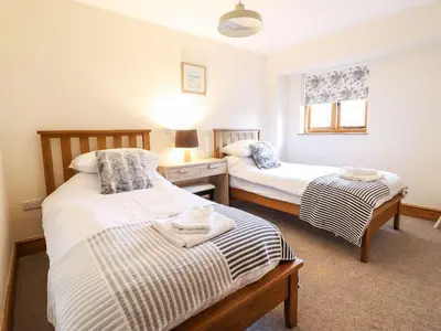 a bedroom with two beds and a window at The Barn in Corwen