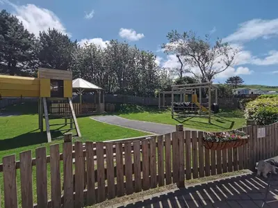 a wooden fence with a playground in a yard at Hiking in Snowdonia? Sea, beach and mountains view in Llwyngwril