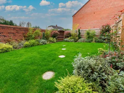 a garden with green grass and a brick building at Contemporary 2 bedroom home - Pass the Keys in Ludlow