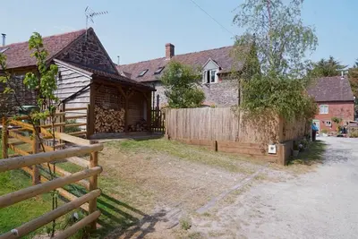 a house with a wooden fence in front of it at Nest Holiday Hideaway Dove Cottage-Beautiful Location in the Long Mynd Area of Outstanding Natural Beauty-WHIRLPOOL JACUZZI BATHS!! in Picklescott