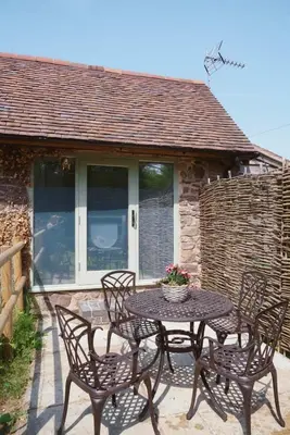 a table and chairs on the patio of a cottage at Nest Holiday Hideaway Dove Cottage-Beautiful Location in the Long Mynd Area of Outstanding Natural Beauty-WHIRLPOOL JACUZZI BATHS!! in Picklescott
