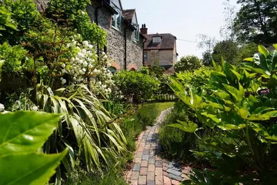 a garden with a brick path in front of a building at Nest Holiday Hideaway Dove Cottage-Beautiful Location in the Long Mynd Area of Outstanding Natural Beauty-WHIRLPOOL JACUZZI BATHS!! in Picklescott