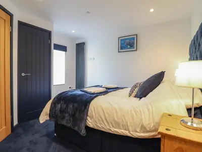 a bedroom with a bed and a table with a lamp at Bryn Eglwys Cottage in Tywyn