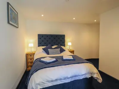 a bedroom with a large bed with two towels on it at Bryn Eglwys Cottage in Tywyn