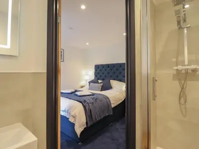 a small bedroom with a bed and a shower at Bryn Eglwys Cottage in Tywyn