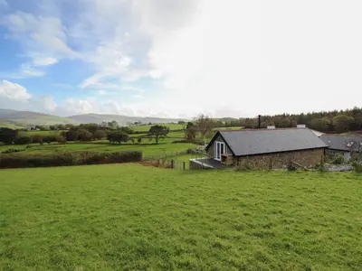 an open field with a barn and a house at Bryn Eglwys Cottage in Tywyn