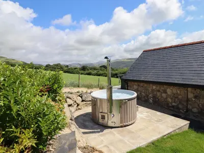 a hot tub in a yard next to a building at Bryn Eglwys Cottage in Tywyn