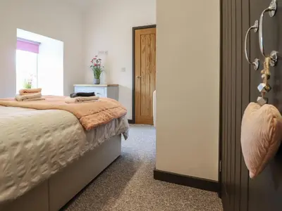 a bedroom with a bed and a door to a room at Bryn Eglwys Barn in Tywyn