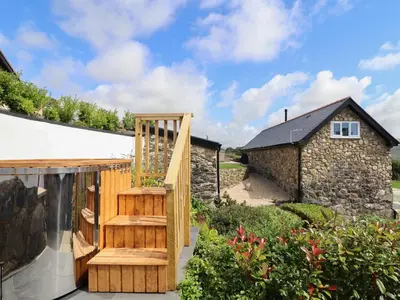 a wooden staircase in a garden with a stone building at Bryn Eglwys Barn in Tywyn