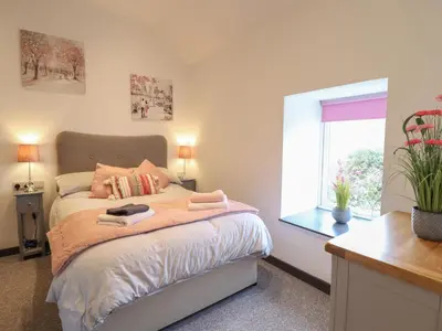 a bedroom with a bed and a window at Bryn Eglwys Barn in Tywyn