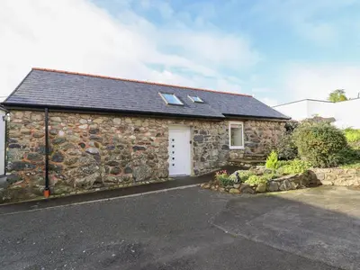 a stone house with a white door and windows at Bryn Eglwys Barn in Tywyn