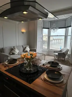 a living room with a table with plates and flowers on it at Swn Y Mor 4 Aberystwyth in Aberystwyth