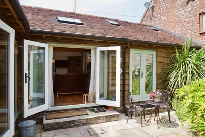 a front porch with glass doors and a table at Nest Holiday Hideaway Wren Cottage-Beautiful Location in the Long Mynd Area of Outstanding Natural Beauty- WHIRLPOOL JACUZZI BATH! in Picklescott
