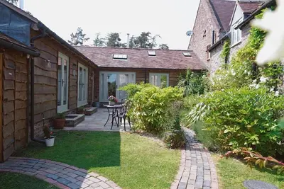 a patio with a table and chairs in a yard at Nest Holiday Hideaway Wren Cottage-Beautiful Location in the Long Mynd Area of Outstanding Natural Beauty- WHIRLPOOL JACUZZI BATH! in Picklescott