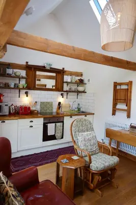 a living room with a table and a kitchen at Nest Holiday Hideaway Wren Cottage-Beautiful Location in the Long Mynd Area of Outstanding Natural Beauty- WHIRLPOOL JACUZZI BATH! in Picklescott