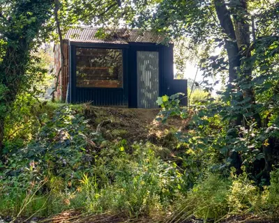 a small house in the middle of a forest at The Boatshed at Camp Plas in Welshpool