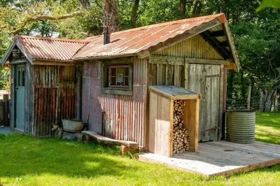 a small wooden shed with a tin roof at The Boatshed at Camp Plas in Welshpool