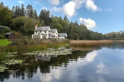a house on the shore of a lake with lily pads at Lake House in Brecon