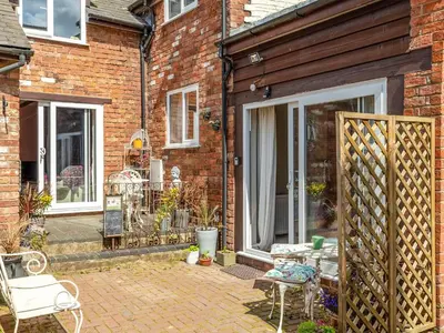 a brick house with a patio with a table and chairs at The Grooms Cottage-Uk45659 in Bishops Castle