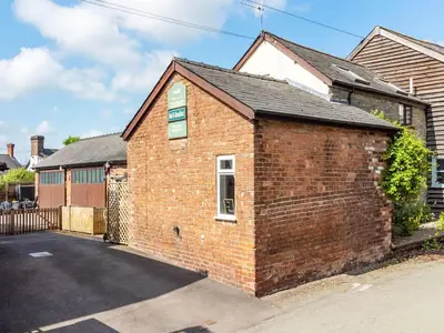 a brick house with a driveway in front of it at The Grooms Cottage-Uk45659 in Bishops Castle