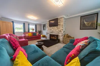 a living room with a blue couch and a fireplace at Parc Y Deri in Aberystwyth