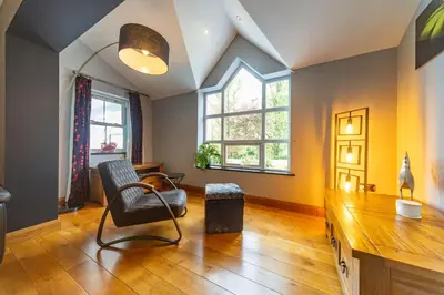a living room with a chair and two windows at Parc Y Deri in Aberystwyth
