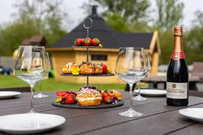 a table with two wine glasses and a plate of food at Parc Y Deri in Aberystwyth