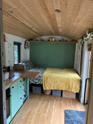 a bedroom with a bed in a tiny house at Transformed Railway Wagon- Sleeps2-Garden-Firepit in Crickhowell