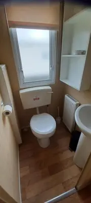 a small bathroom with a toilet and a sink at Caravan 76 snowdon summit 016 in Talybont
