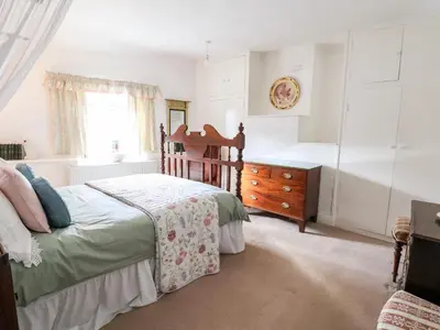 a bedroom with a bed and a dresser and a window at Wharf Cottage in Llangollen