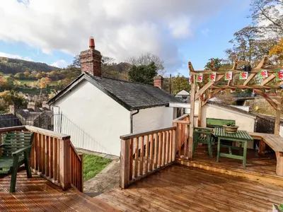 a wooden deck with a table and a pergola at Wharf Cottage in Llangollen