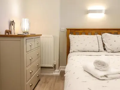 a bedroom with a bed and a dresser with a lamp at Tan Isa in Harlech