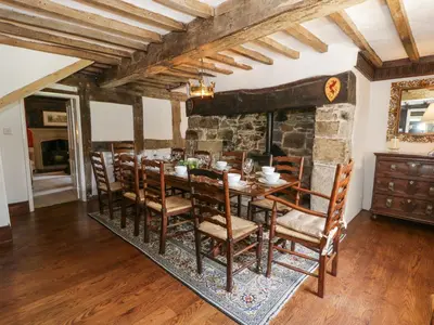 a dining room with a table and a stone wall at Pentre Hall in Oswestry