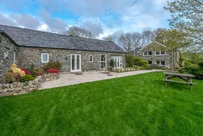 a stone house with a green lawn in front of it at Stabal-Byrdir in Dyffryn