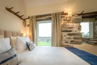 a bedroom with a large bed and a stone wall at Stabal-Byrdir in Dyffryn