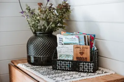 a black vase sitting on a table with books at Secluded Cosy Luxury Pod with wood fired hot tub in Shrewsbury